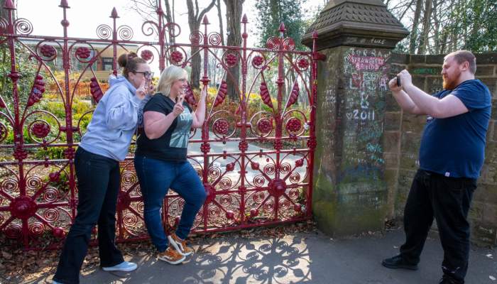 Two women smiling and posing while having their picture took by a man in-front of the Strawberry Fie…