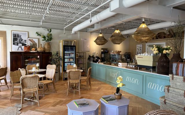 A brightly lit cafe with a teal counter, tables and chairs.