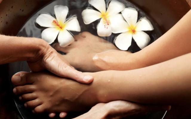 a person's feet being massaged in a foot bath with flowers