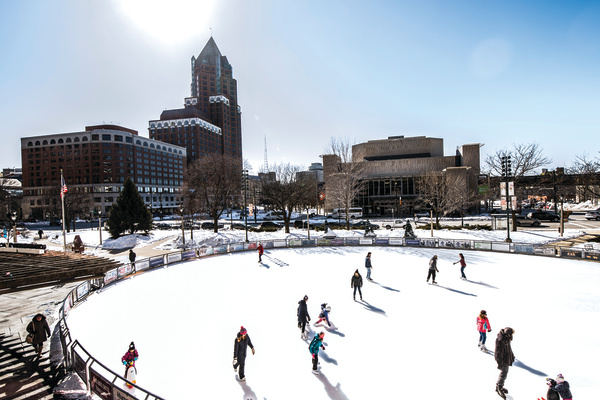 ice skaters at Red Arrow Park with city behind