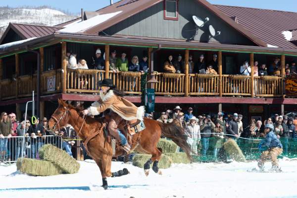 Photo of a woman on horseback pulling a skier on Grand Avenue at the 2025 Grand Lake Skijoring event