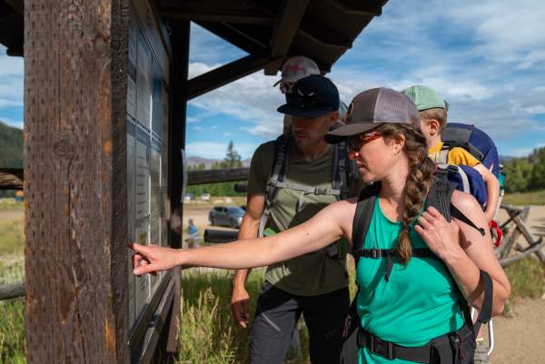 Family with young children looking at trail head map