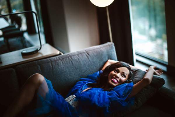 A woman in a blue dress relaxes on a hotel couch