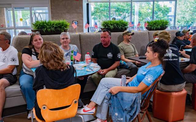 Group of adults seated together at tables, talking and reconnecting during a casual reunion gathering in Greater Fayetteville.