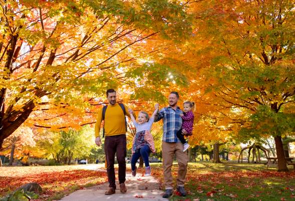 Family with two dads and daughters walking at Aldo Leopold Nature Center in Madison surrounded by vibrant fall foliage