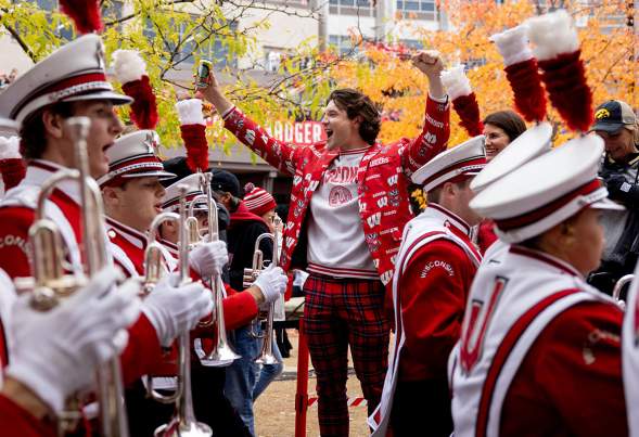 Badgers football sports fan cheering in Madison, WI with a marching band playing instruments