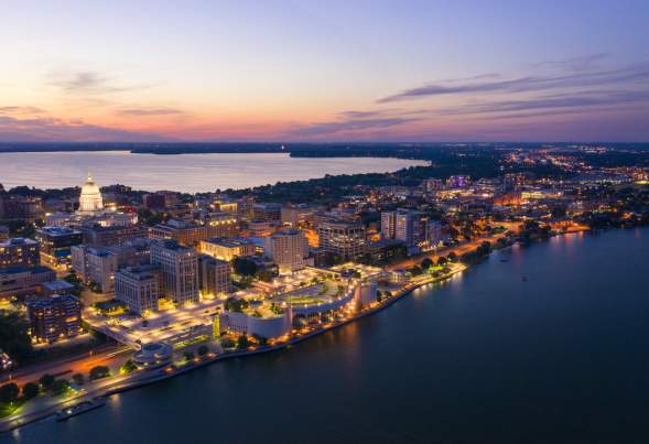 An aerial view of Downtown Madison and the isthmus lit up as dusk approaches