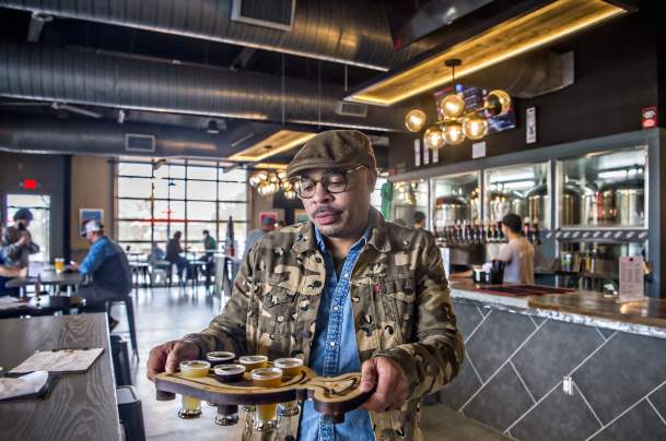 Man walking to table at brewery carrying beer