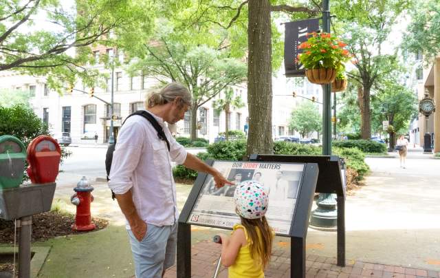 Father and daughter looking at a historic marker