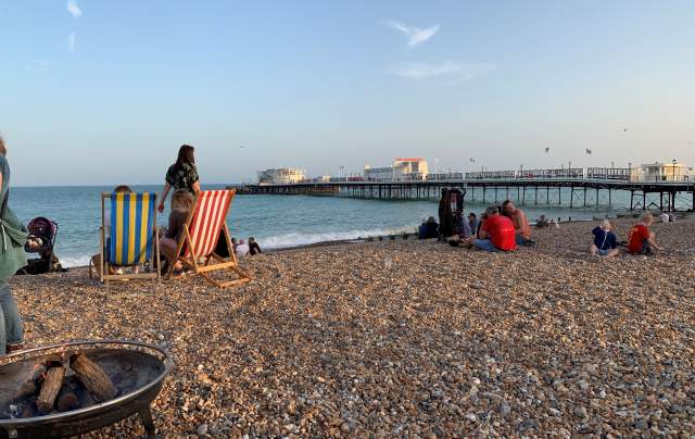 Group of people enjoying a BBQ on the beach at Worthing, with a view of Worthing Pier