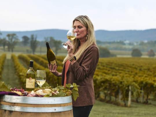 Woman sipping award-winning wine with a scenic backdrop of Breaux Vineyards