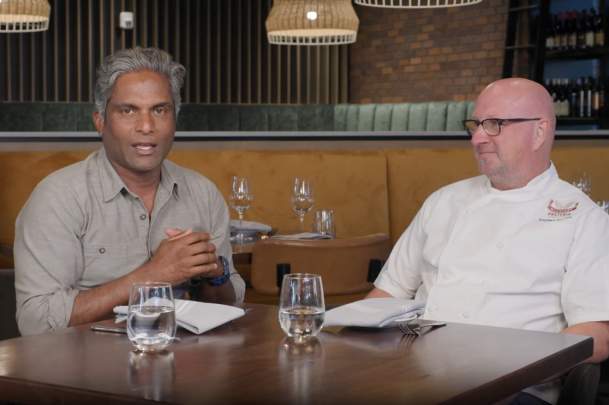 Two men sit at a table in a warm and cozy restaurant.