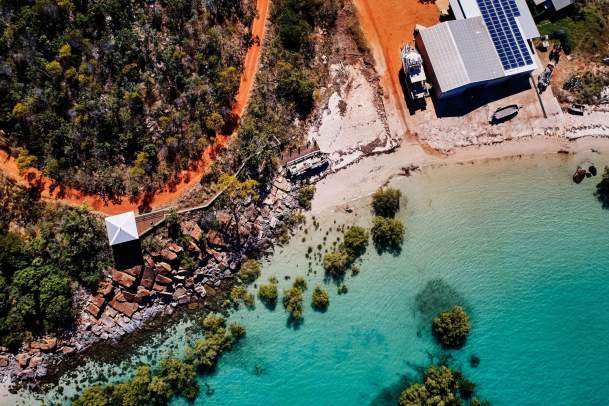 Overhead view of coastline at Cygnet Bay showing the red coloured pindan soil, white sand, turquoise waters as well as the mangroves and rocks