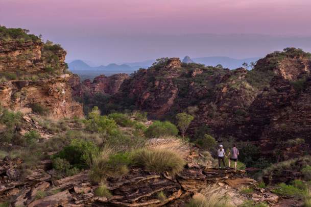 A couple standing on the rock formations in Mirima National Park at, with deepending pink colours in the sky