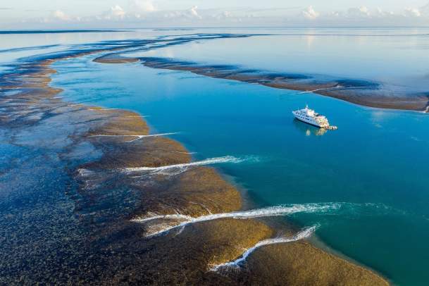 Aerial shot of the True North cruise ship at Montgomery Reef on the Kimberley Coast with the tide starting to recede from the reef