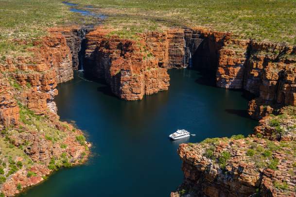 A drone view of an expedition cruise ship at Oomari King George Falls on the Kimberley Coast, with the twin waterfalls still in flow