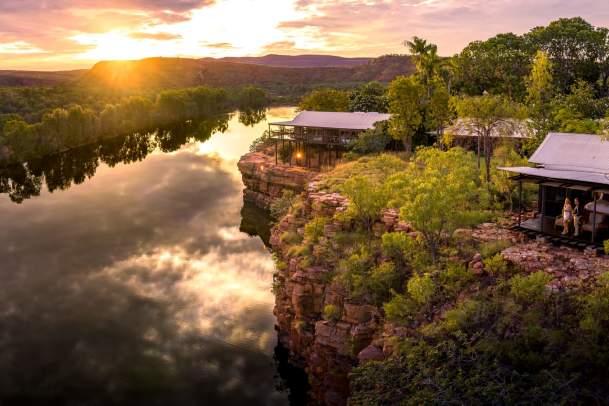 A couple standing outside the Cliffside Rooms at El Questro The Homestead, with more accommodation shown behind them and a sweeping view of Chamberlain Gorge