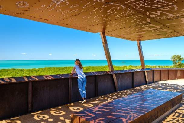 Woman standing at the Roebuck Bay lookout in Chinatown Broome, looking towards the waters of Roebuck Bay