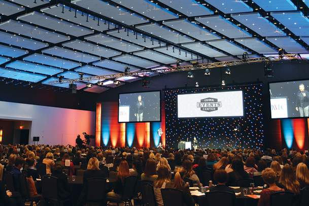 Man speaking on stage to a large room of attendees at the Iowa Events Center