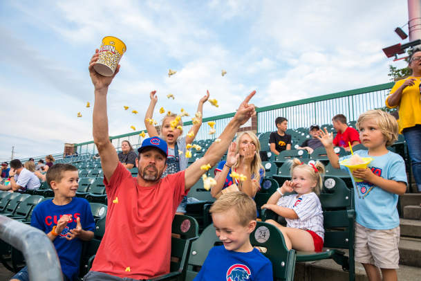 Fans at an Iowa Cubs game throwing popcorn in the air and cheering