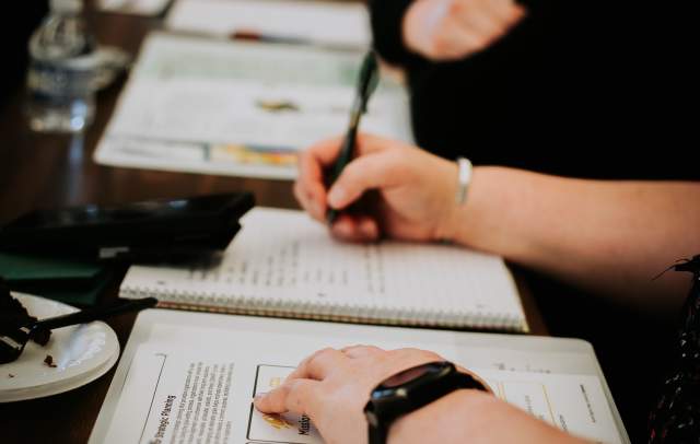A person taking notes and writing in a binder.