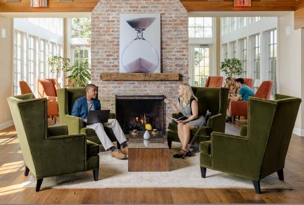 Two people sit across from one another discussing a presentation.