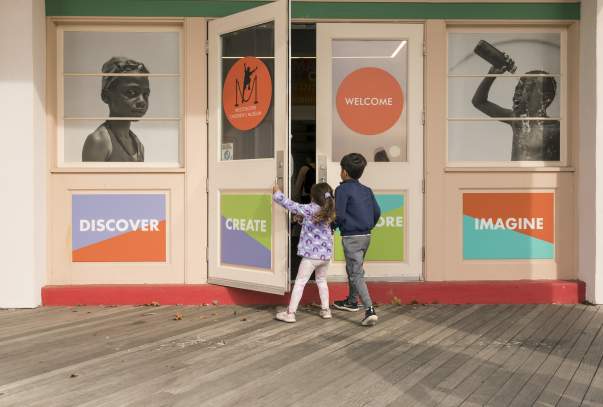 Two children are opening the door of the Westchester Children's Museum.