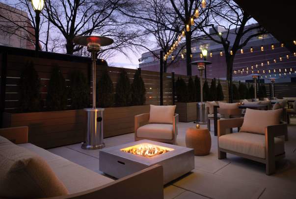 An outdoor patio at the Sonesta White Plains with a firepit and cushioned chairs.