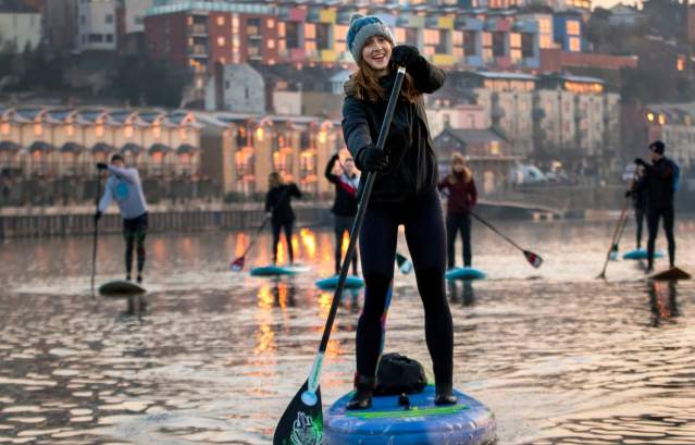 A group of people stand-up paddleboarding in Bristol Harbour - credit Paul Box