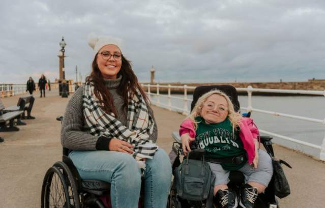Two women exploring a pier. One is in a mobility scooter, the other in a wheelchair. CREDIT VisitBritain/Purple Goat/Isobel Greenhalgh