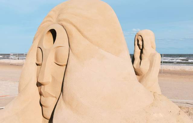 A large sand sculpture of a person's face resting on a hand at Texas SandFest.