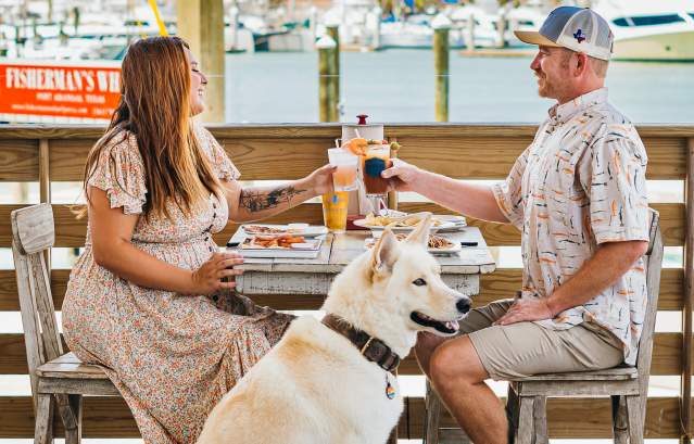 Women and man sitting at a table at the Grubmles resturant outside. They have a white husky dog sitting at their feet.