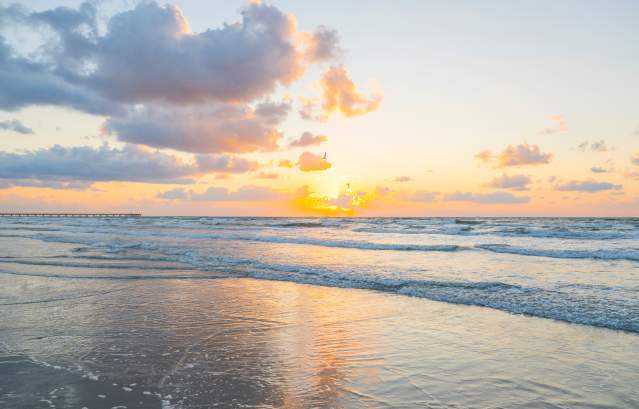 A bright, golden sunrise over the ocean waves on a beach in Port Aransas.