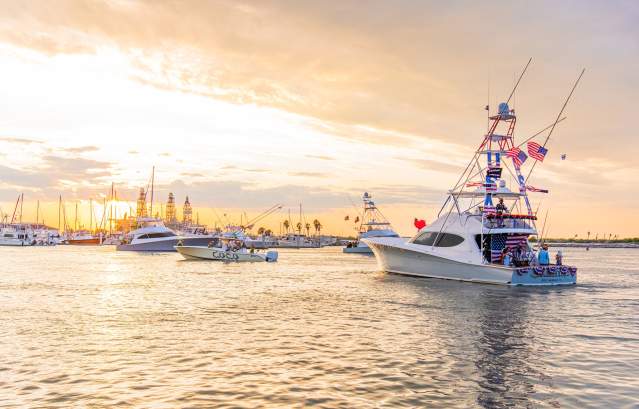 Several boats, decorated in various theme, head away from the camera