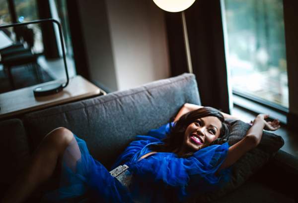 A woman in a blue dress relaxes on a hotel couch