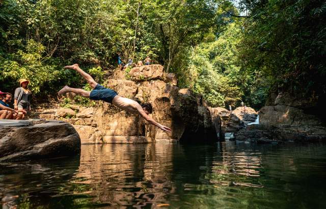 One person dives into the river with open arms, while another relaxes on a rock in Penonome