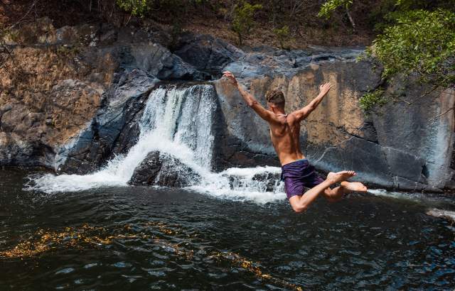 Someone embarking on a thrilling water jump near the waterfall.