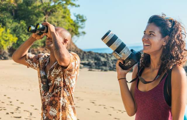 A party of people with cameras is on a beach exploration journey.
