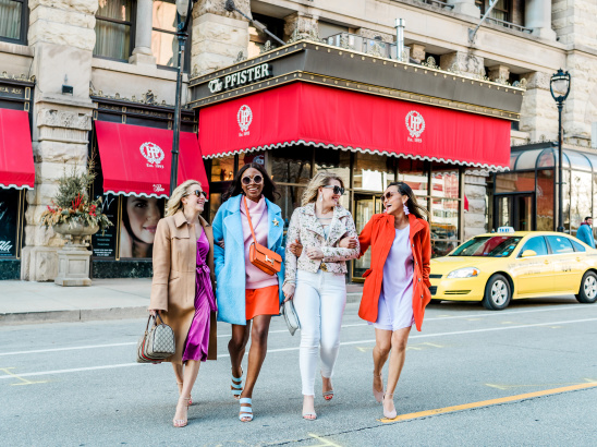 group of friends interlocking arms and walking in front of the Pfister Hotel