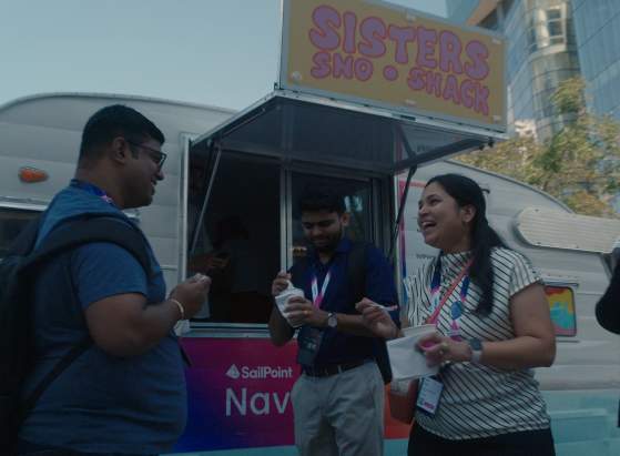 Three meeting attendees smiling and talking next to a food truck.