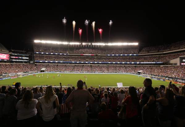 Fireworks blasting over a stadium at night filled with people