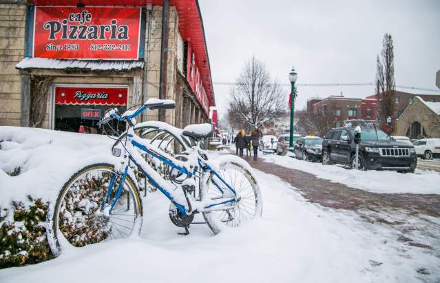 A bike covered in snow on Kirkwood Avenue in front of Cafe Pizzaria