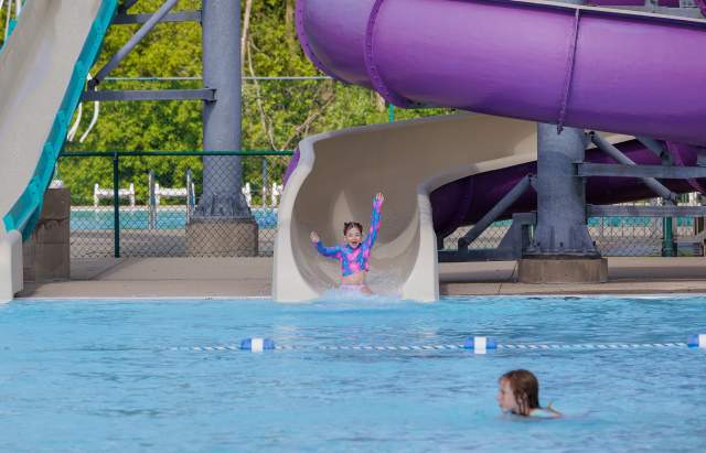 Girl with arms up riding down the purple water slide at Woodstock Water Works