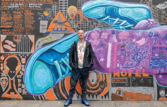 Karl, an artist, standing in front of his art