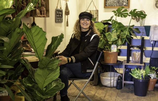 Florist sat in her shop surrounded by plants.