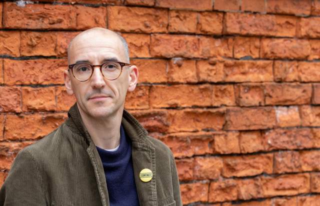 Matt Fenton Director of Contact Theatre stood against brick wall