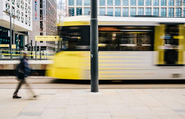 Tram moving and person walking at tram stop