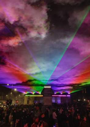 Lightport at Monument Square in Southport, image shows rainbow coloured lasers over a crowded Monument Square