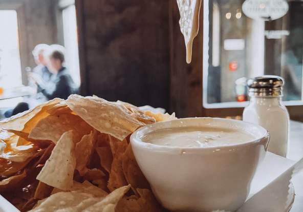 beer cheese dip dripping from chip
