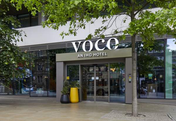 The front doors of voco hotel Manchester with sustainable green plants out front.